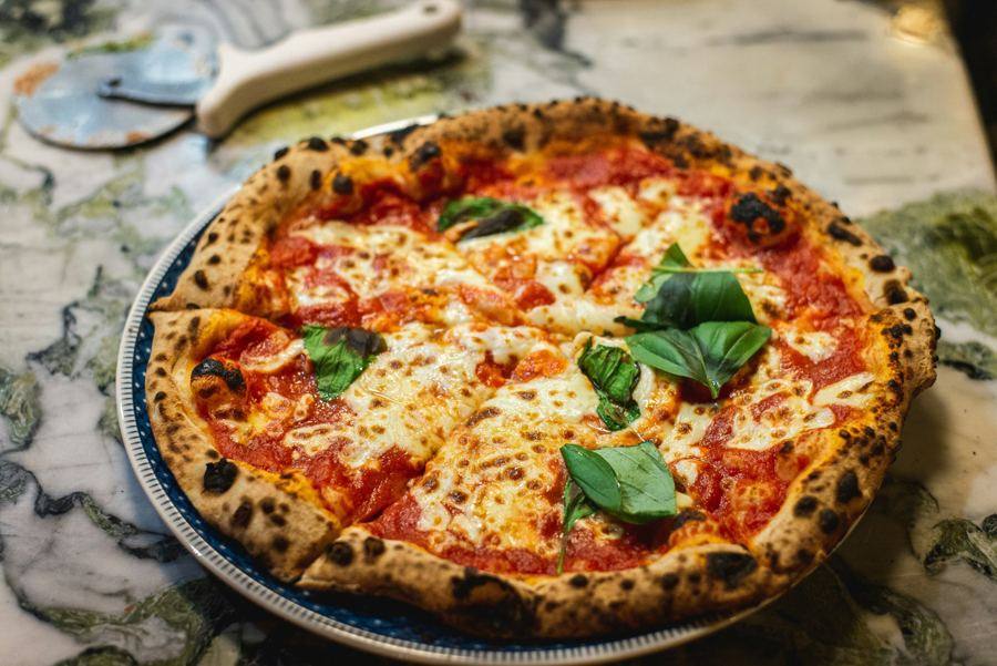 Neapolitan pizza in front of a wood-fired oven