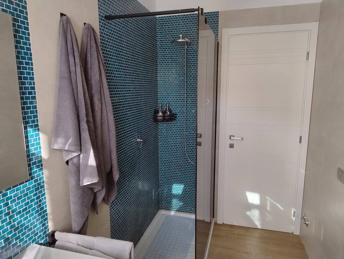Walk-in shower with rain shower head and blue mosaic
